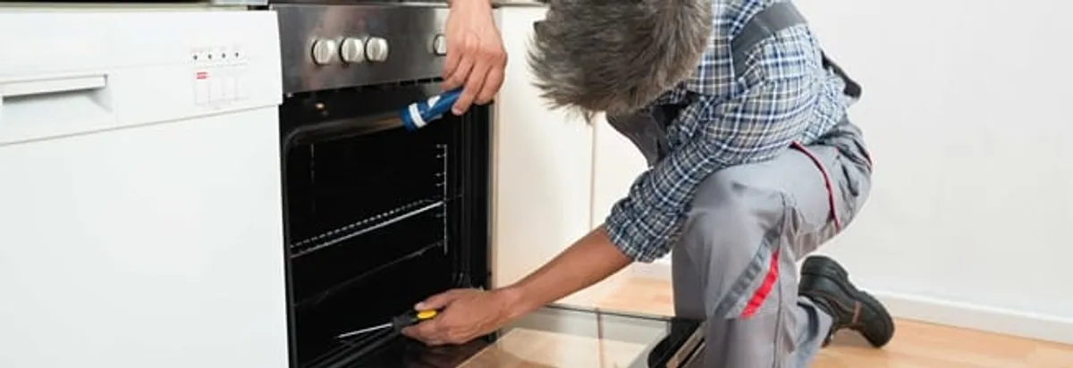 Oven repair technician inspecting and servicing an electric oven in Jacksonville, FL