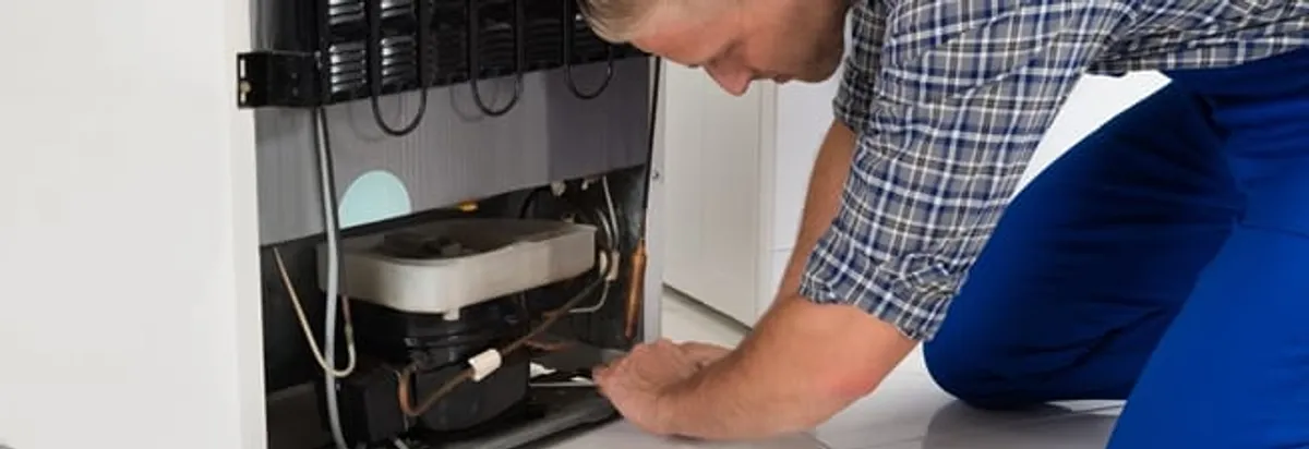 Refrigerator repair technician servicing the compressor and condenser area in Jacksonville, FL