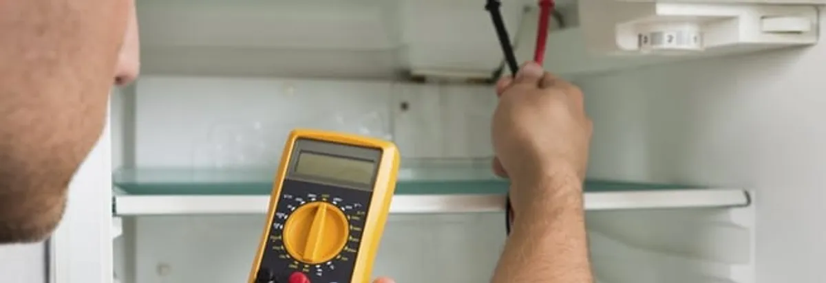 Refrigerator repair technician testing electrical components with a multimeter in Jacksonville, FL